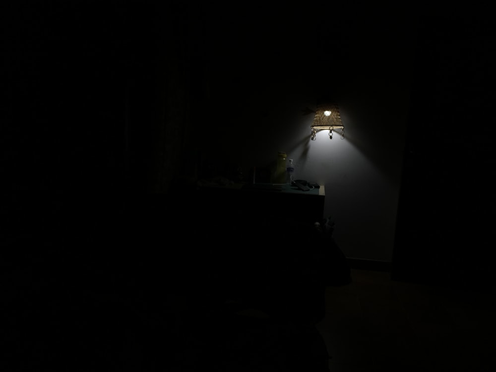 a dark room with a lamp on the wall