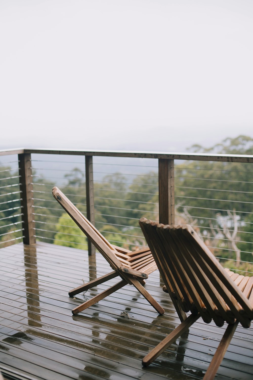 zwei braune Klapp-Liegestühle aus Holz auf dem Balkon