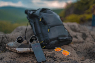 A stylish pair of slip-on shoes placed beside a backpack and sunglasses.