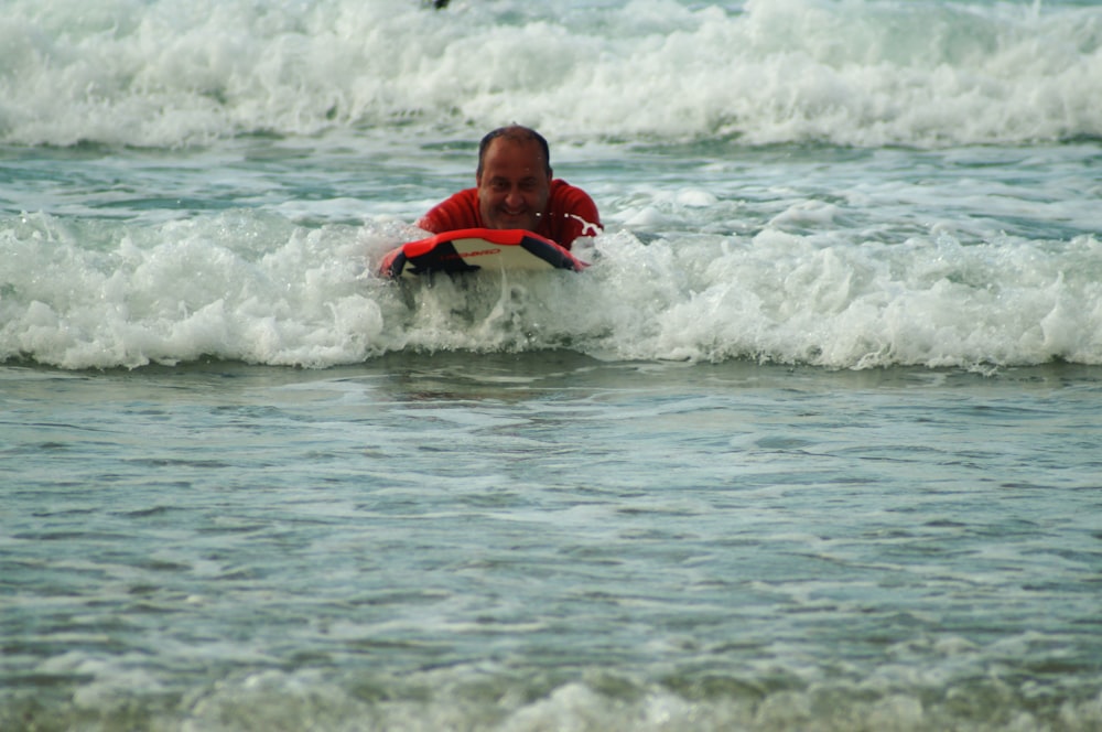 man riding surfboard on body of water during day