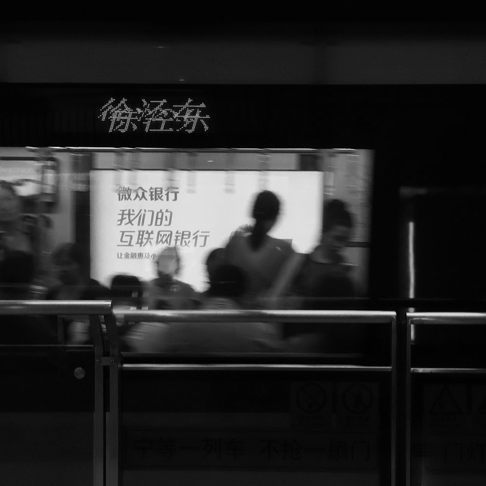grayscale photography of people inside building with glass wall