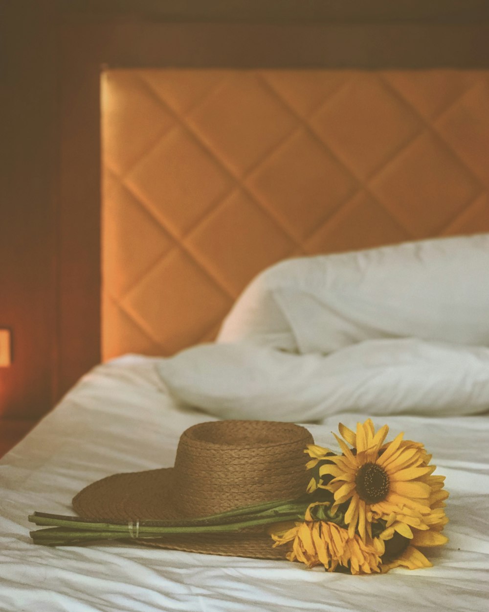 침대에 갈색 태양 모자 옆에 노란 해바라기