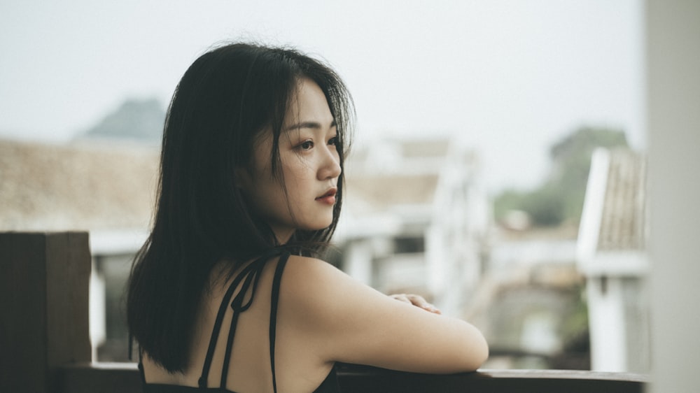 selective focus photography of woman leaning on black wood looking at her right