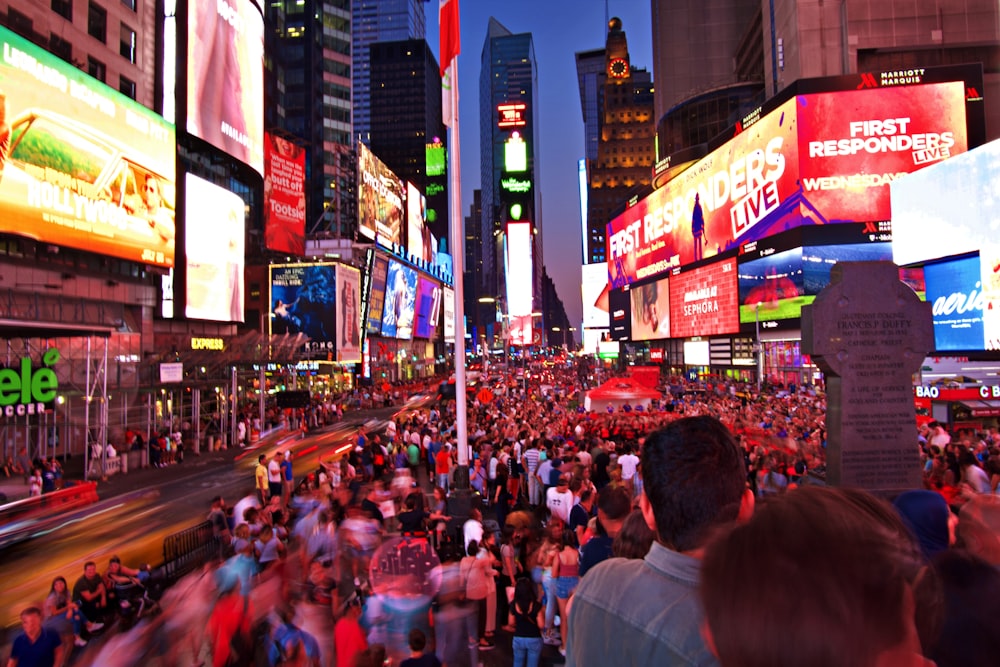 crowd on road between buildings with electric billboards