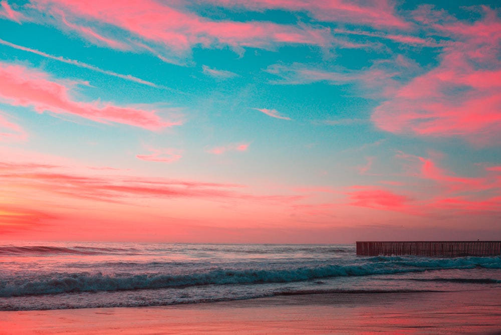 body of water under pink and blue sky during golden hour