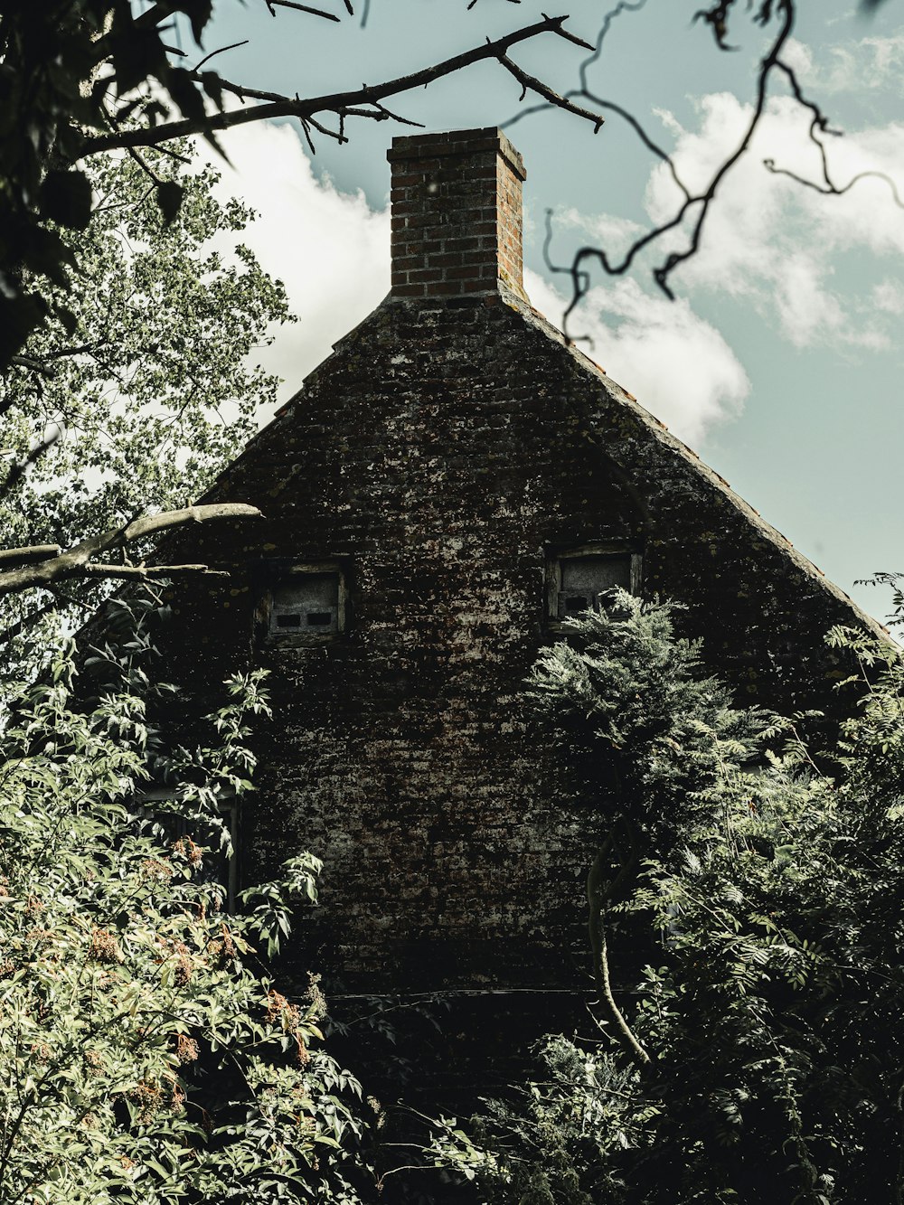 gray bricked house with chimney beside trees during daytime