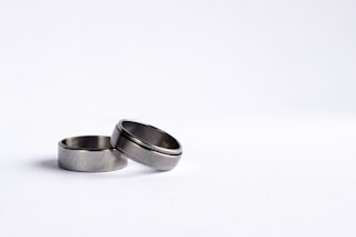 Two silver rings placed on a plain white background with one ring slightly leaning against the other.
