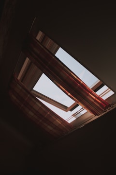 View of a roof window equipped with a custom mosquito screen under a sunny sky.