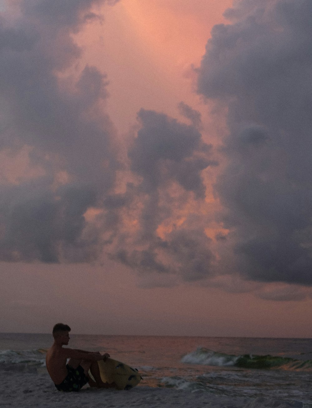 man with a yellow surfboard at a beach