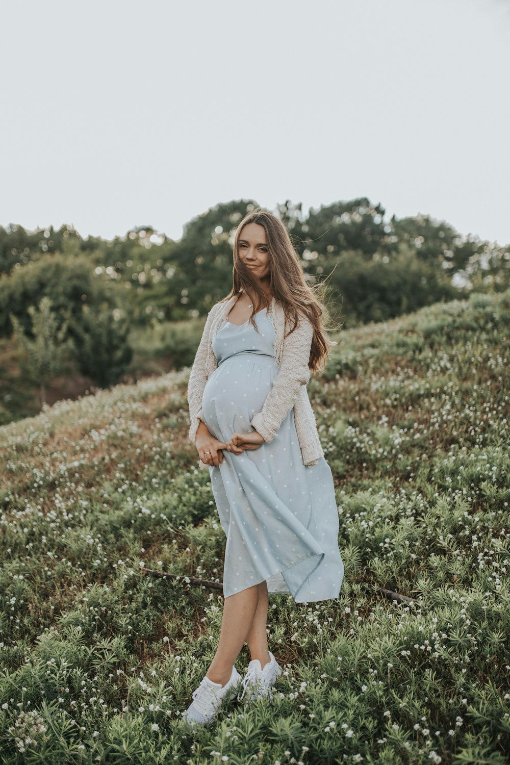 pregnant woman wearing gray dress standing on green grass during daytime