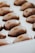 A series of glossy, oval-shaped chocolates arranged neatly in a white tray. The chocolates have a smooth, shiny surface with a rich, dark brown color.