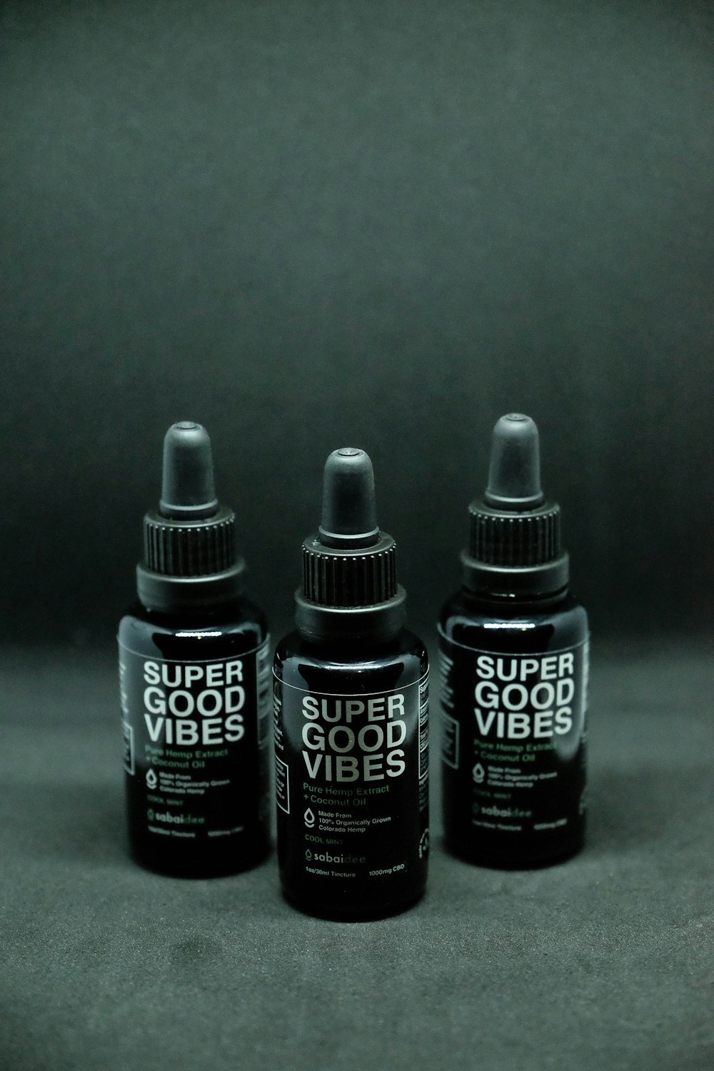 three black and white Super Good Vibes dropper bottles