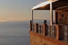 A spacious balcony overlooking a serene beach at sunset.