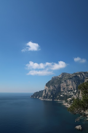 The Amalfi Coast’s dramatic cliffs meeting the sparkling blue sea under a clear sky.