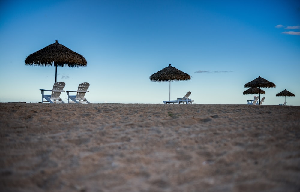 a beach with chairs and umbrellas on the sand