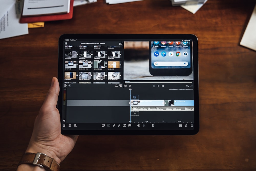 person holding black tablet computer showing video editor