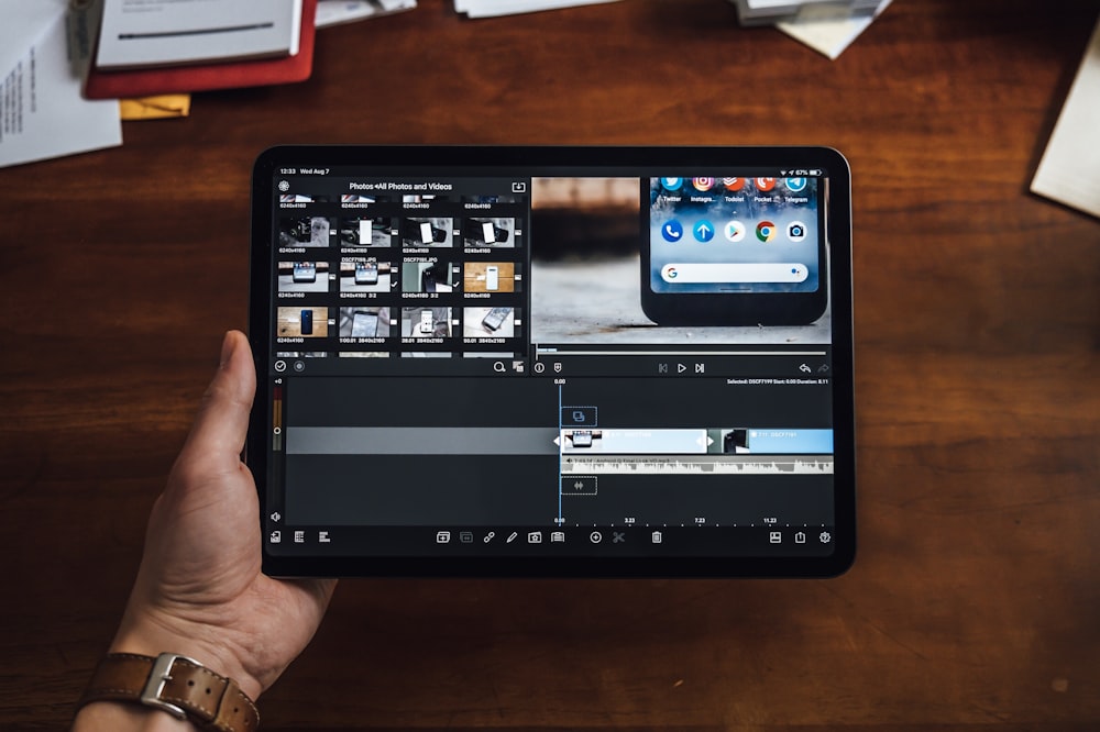 Persona sosteniendo una tableta negra que muestra el editor de video