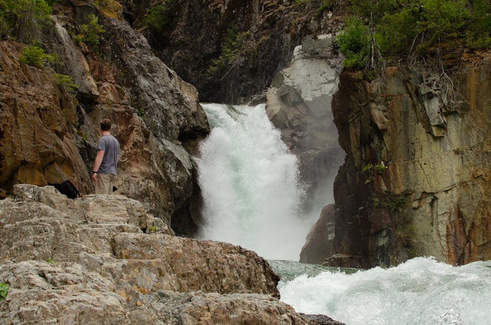 man standing near waterfall