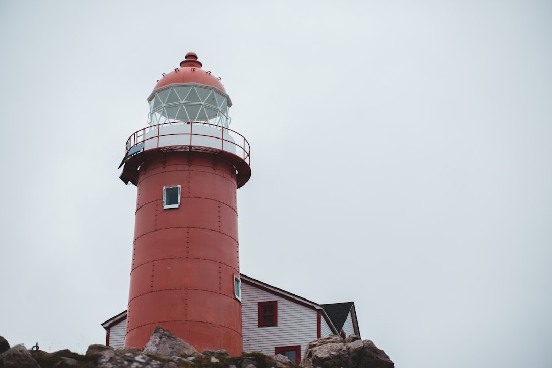 red and white concrete lighthouse under gray sky