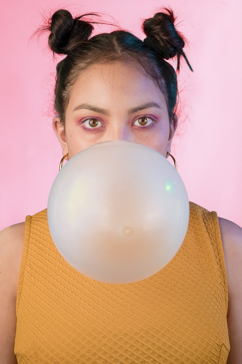 woman in yellow sleeveless shirt blowing gum