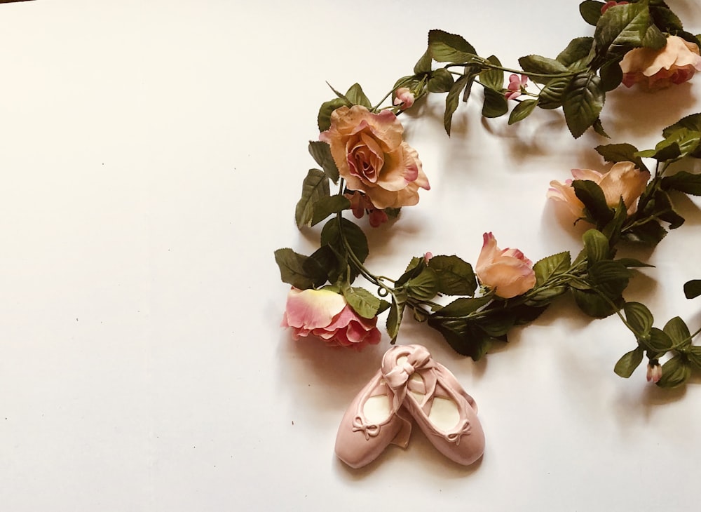 pair of pink ballerina flats ceramic figurine besides flower wreathes