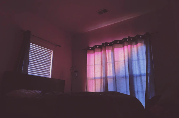 Cozy bedroom with deep blue blackout curtains softly drawn over the window at twilight.