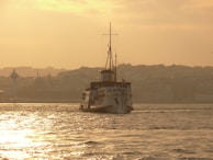 A ship navigating through calm waters with a sunset backdrop.