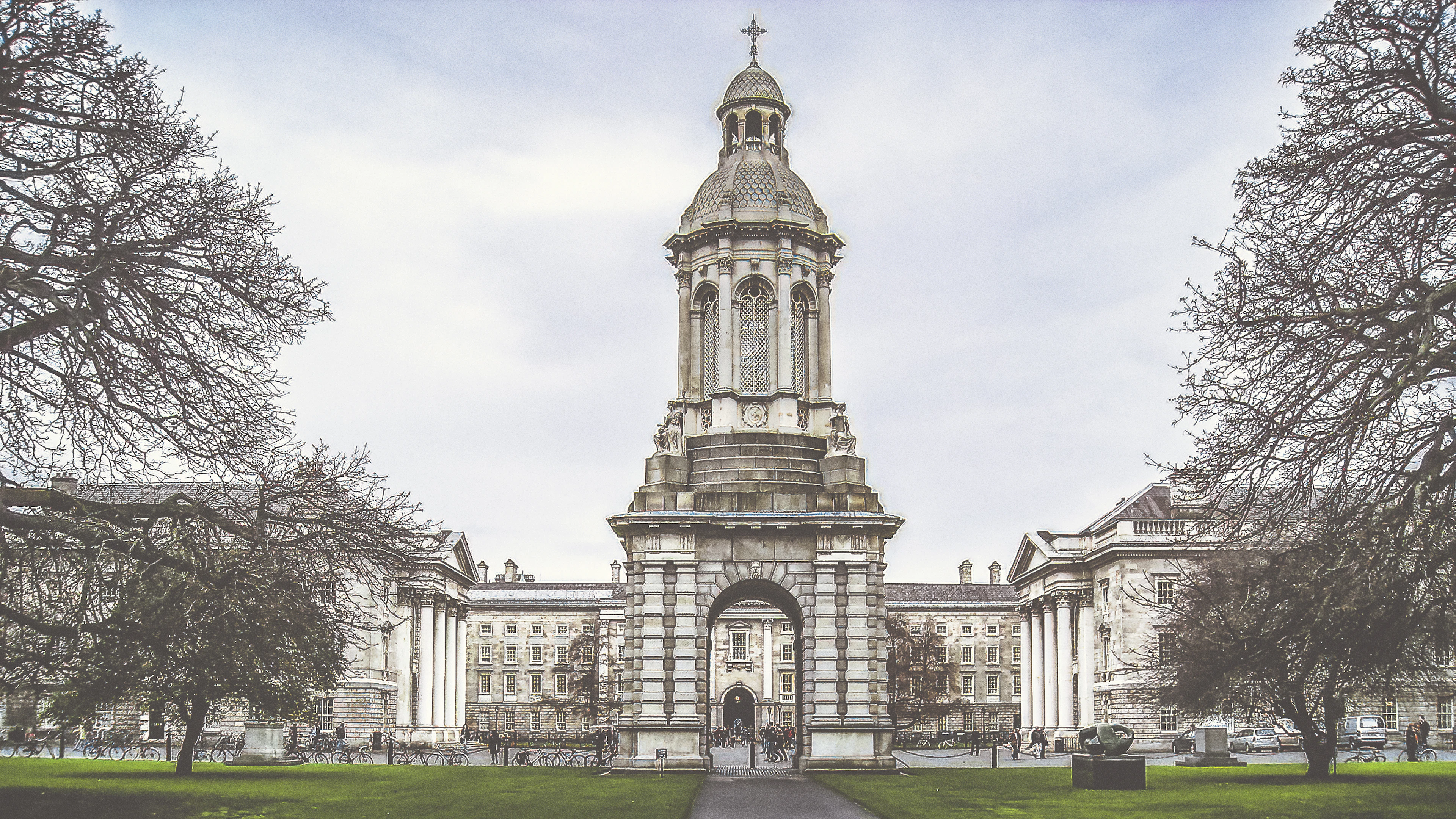 The stone Campanile standing at the centre of Parliament Square at Trinity College Dublin, framed symmetrically by bare winter trees with the colonnaded Chapel and Examination Hall on either side