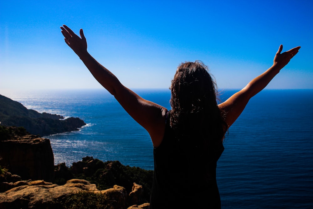 a woman standing on top of a mountain with her arms outstretched