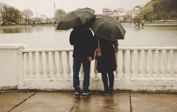 man and woman holding black umbrellas