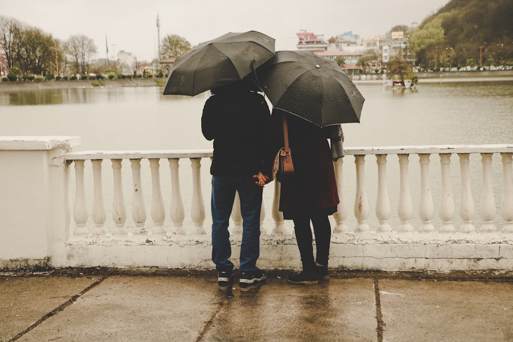 man and woman holding black umbrellas