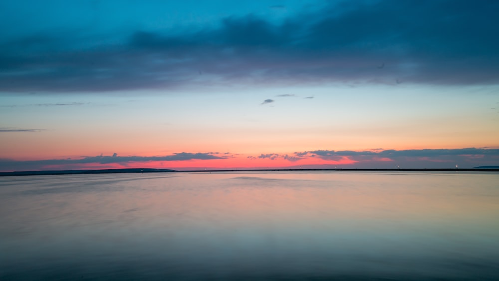 mar azul en calma bajo cielos naranjas y azules