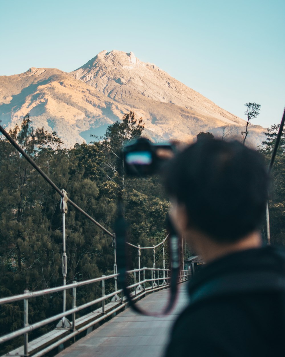man taking photo of brown mountain