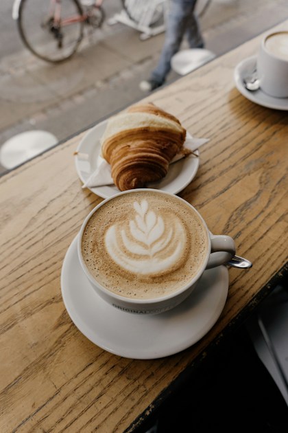 Cappuccino avec latte art et cornetto sur table en bois, brunch à l'italienne