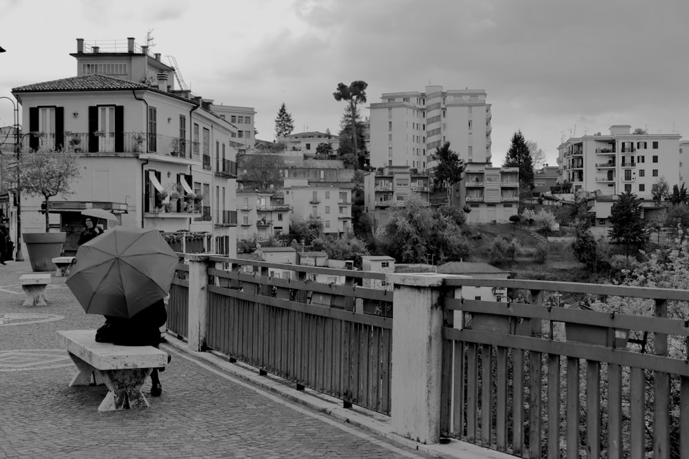 grayscale photography of person sitting on bench with umbrella