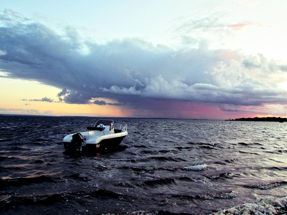 Weißes Boot im Gewässer unter weißen Wolken während des Tages