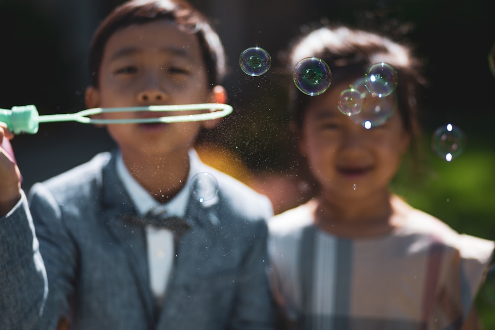 two kid near bubbles during daytime