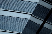 A close-up view of a layered, textured surface with diagonal lines and alternating light and dark patterns. The design appears metallic with a modern, industrial aesthetic, showcasing intricate details in the ribbed texture.
