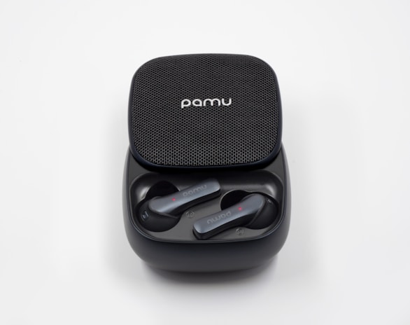 Noise-cancelling earbuds resting inside their compact charging case on a bedside table.