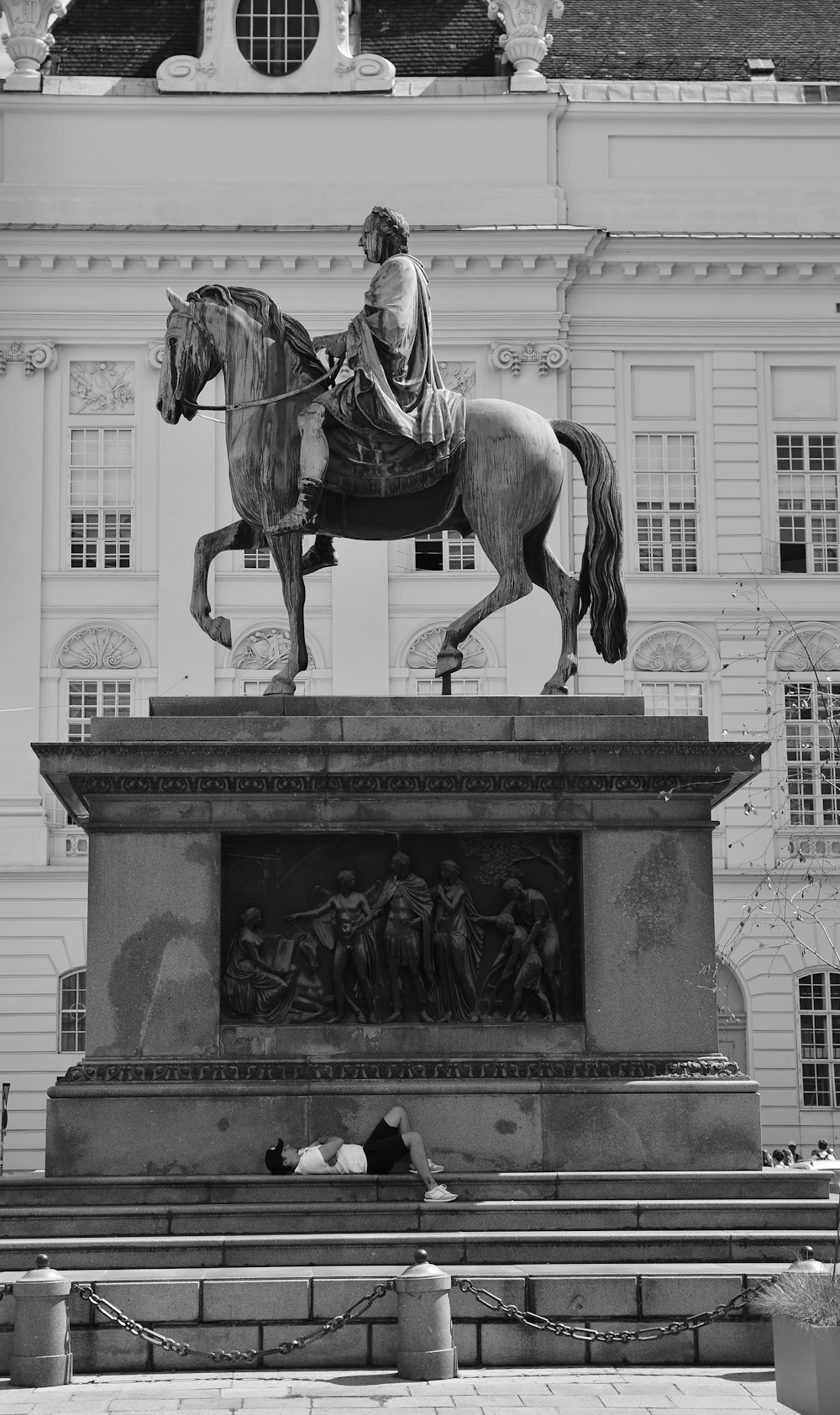 man sleeping on stairs beside man riding horse statue