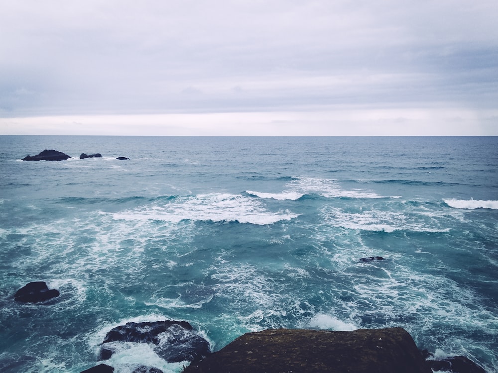 rocks in the sea under white clouds