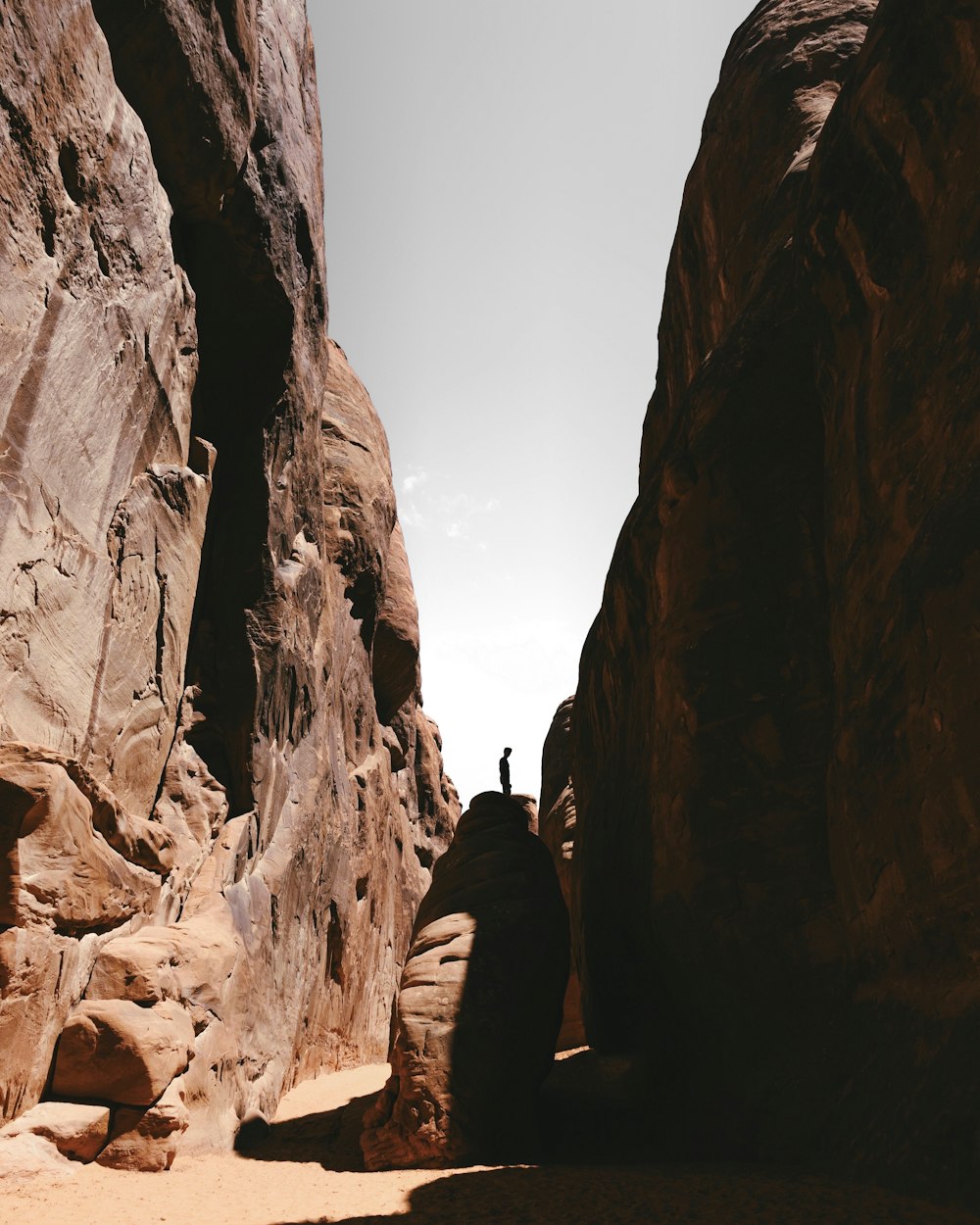 silhouette of person standing on rock boulder