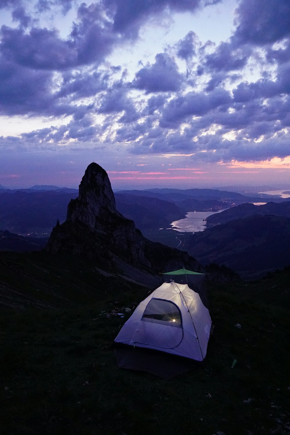 lighted tent on mountain top under clouded sky