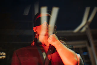 A moody, cinematic shot of a model wearing oversized black streetwear with glowing red details, set against a black gradient background.