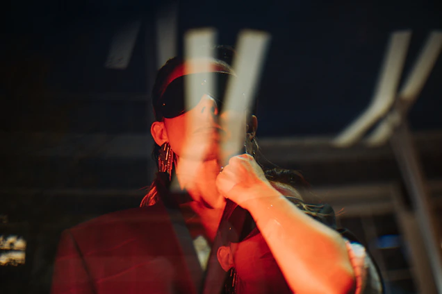 A moody, cinematic shot of a model wearing oversized black streetwear with glowing red details, set against a black gradient background.