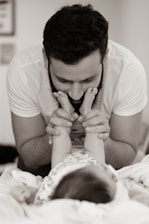 grayscale photography of man playing with baby