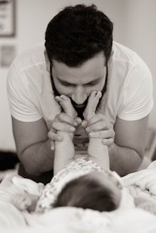 grayscale photography of man playing with baby