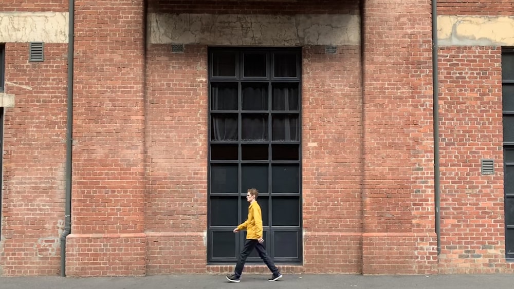 man walking beside wall