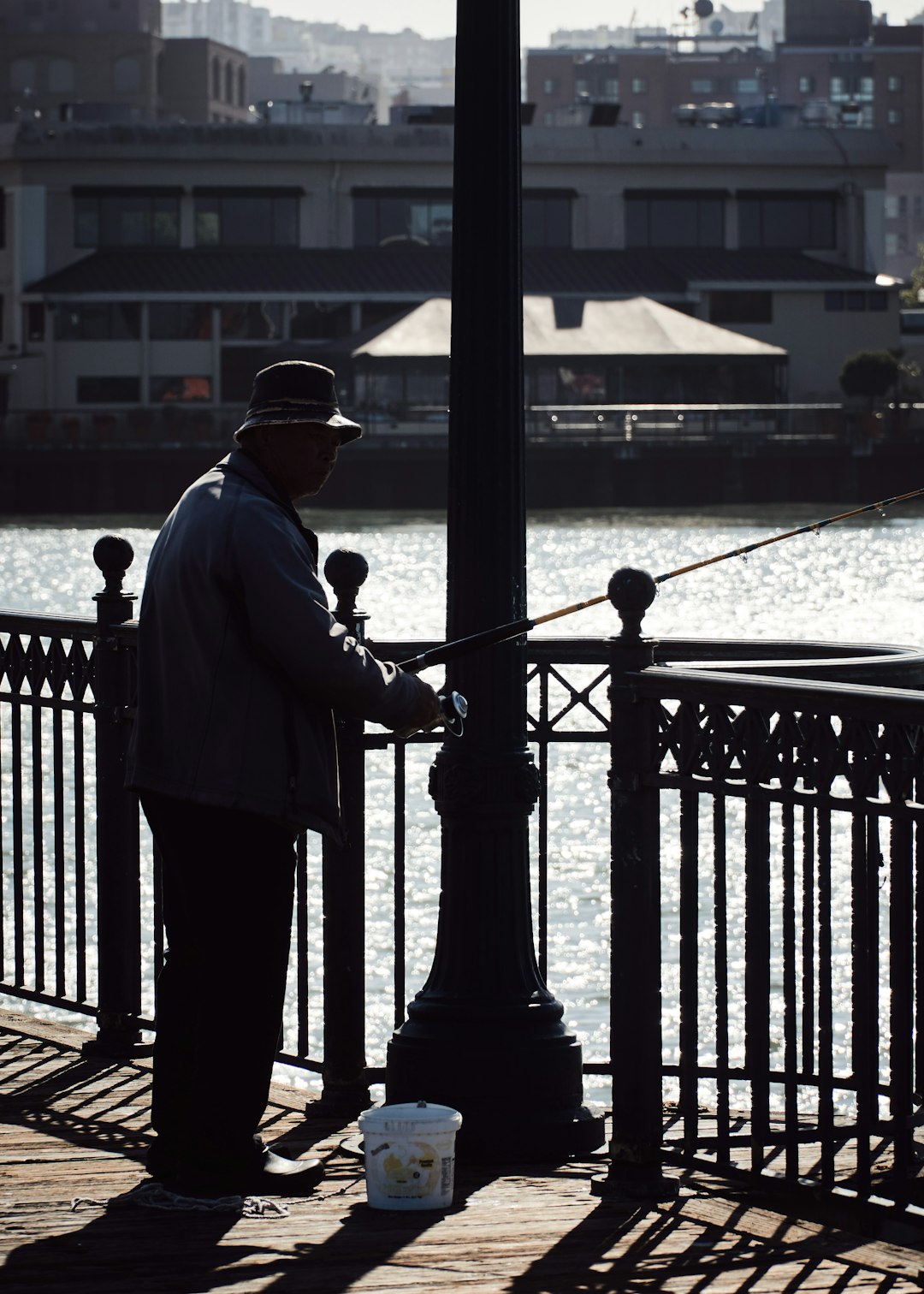 man holding fishing rod while standing near metal post