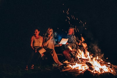 people sits in front of fire bonfire teams background